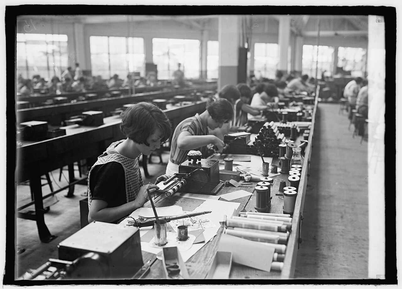 Figure 4 — Wire being laid onto a former; the operator watches the feed and tension while the controller counts turns and drives the traverse. Source: "Winding transformer coils," U.S. Library of C…